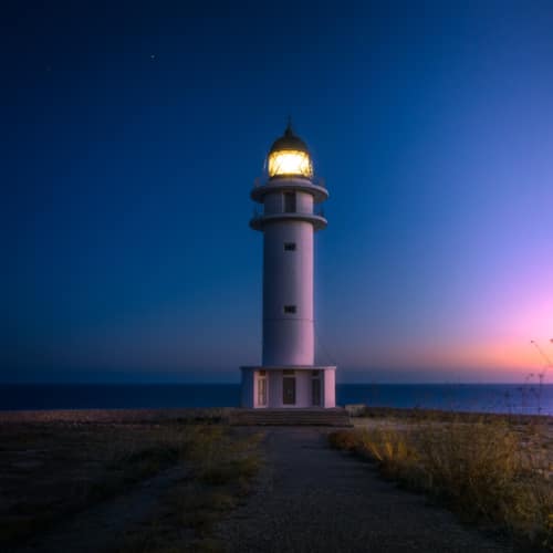 lighthouse in front of a dark bluge sky
